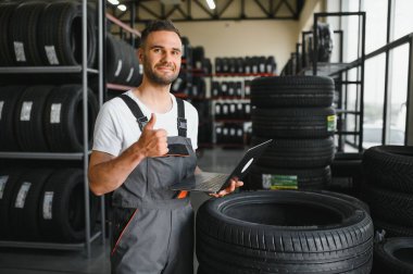 Araba servisindeki müşteri lastiği montajı, otomobil tamircisi güvenlik için lastiği ve lastik lastiği kontrol ediyor, konsept: makinelerin tamiri, hata tanısı, onarım. Adam araba tamirhanesinden alışveriş yapıyor.