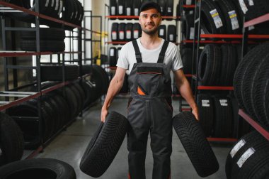 Araba servisindeki müşteri lastiği montajı, otomobil tamircisi güvenlik için lastiği ve lastik lastiği kontrol ediyor, konsept: makinelerin tamiri, hata tanısı, onarım. Adam araba tamirhanesinden alışveriş yapıyor.