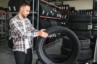 Adam araba tamirhanesinde kış lastiklerini seçiyor..