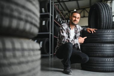 Adam araba tamirhanesinde kış lastiklerini seçiyor..