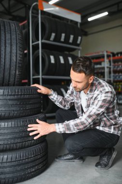Araba servisindeki müşteri lastiği montajı, otomobil tamircisi güvenlik için lastiği ve lastik lastiği kontrol ediyor, konsept: makinelerin tamiri, hata tanısı, onarım. Adam araba tamirhanesinden alışveriş yapıyor.