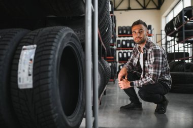 Adam araba tamirhanesinde kış lastiklerini seçiyor..