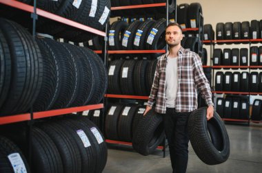 Adam araba tamirhanesinde kış lastiklerini seçiyor..