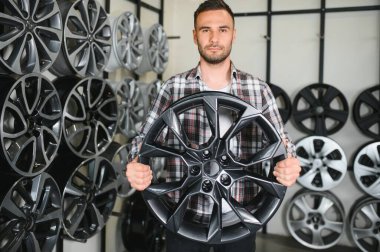 Adam araba dükkanında yeni alaşım tekerlekleri seçiyor..