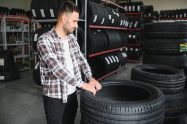 Genç bir adam arabası için yeni lastikler alır..