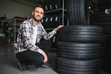 Adam araba tamirhanesinde kış lastiklerini seçiyor..