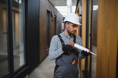 Bir işçi yeni bir modüler eve pencere takıyor. Yeni ev kavramı..