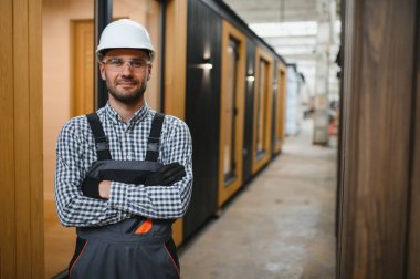 Prefabrik ahşap evin yanındaki üniformalı işçinin portresi..