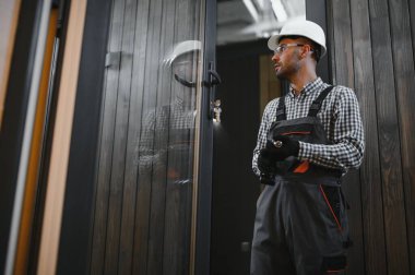 Üniformalı bir işçi ya da mühendis ahşap modüler evler için inşaat alanında çalışıyor..