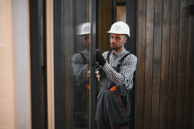 Üniformalı bir işçi ya da mühendis ahşap modüler evler için inşaat alanında çalışıyor..