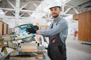 Profesyonel marangoz kereste fabrikasında tahta kesmek için testere makinesi kullanıyor..