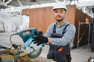 Profesyonel marangoz kereste fabrikasında tahta kesmek için testere makinesi kullanıyor..