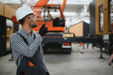 Foreman telsiz kullanarak prefabrik modüler bir evi kamyondan kamyona yüklüyor..