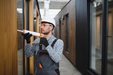 Bir işçi yeni bir modüler eve pencere takıyor. Yeni ev kavramı..