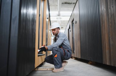 Bir işçi yeni bir modüler eve pencere takıyor. Yeni ev kavramı..