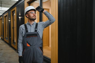 Prefabrik ahşap evin yanındaki üniformalı işçinin portresi..