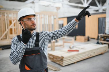 Bir mühendis modüler evlerin üretimini kontrol ediyor ve bir telsiz kullanıyor..