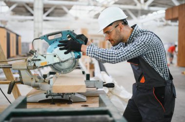 Profesyonel marangoz kereste fabrikasında tahta kesmek için testere makinesi kullanıyor..