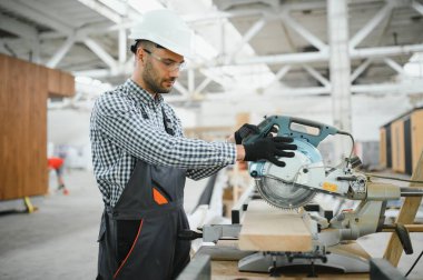 Profesyonel marangoz kereste fabrikasında tahta kesmek için testere makinesi kullanıyor..