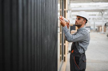 Bir işçi yeni bir modüler eve pencere takıyor. Yeni ev kavramı..