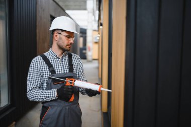 Bir işçi yeni bir modüler eve pencere takıyor. Yeni ev kavramı..