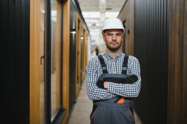 Yeni ve modern modüler evin inşaatı. Özel koruma üniformalı işçiler enerji tasarruflu mülklerin geliştirme endüstrisinde çalışıyor..