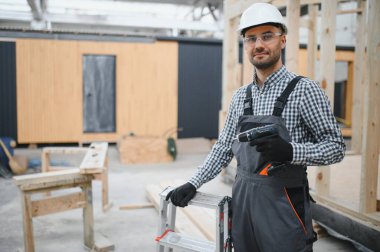 Prefabrik ahşap evin yanındaki üniformalı işçinin portresi..