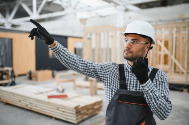 Bir mühendis modüler evlerin üretimini kontrol ediyor ve bir telsiz kullanıyor..