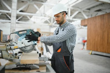 Üniformalı bir işçi ya da mühendis ahşap modüler evler için inşaat alanında çalışıyor..