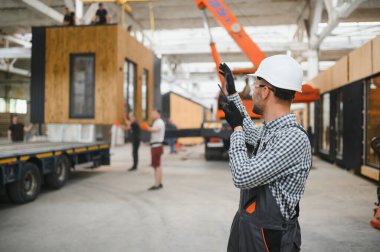 Bir işçi modüler evi kamyona yükleme işlemini kontrol eder. Ulaşım ve teslimat kavramı.