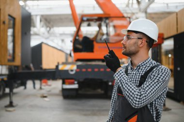 Bir işçi modüler evi kamyona yükleme işlemini kontrol eder. Ulaşım ve teslimat kavramı.