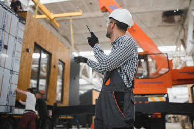 Bir işçi modüler evi kamyona yükleme işlemini kontrol eder. Ulaşım ve teslimat kavramı.