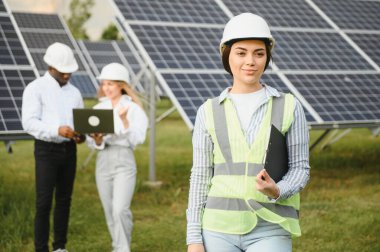 Group of investors together with young lady ecological engineer they analysing the plan of work and the efficient operation of solar batteries.