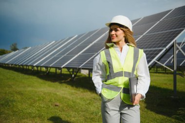 Güneş panelleri ve dizüstü bilgisayarı olan bir yatırımcı. Güneş panelleri yakınında dizüstü bilgisayarı olan bir iş kadını. Ev ve iş için yeşil enerji.