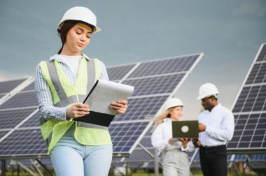 Bir grup mühendis güneş paneli çiftliğinde çalışıyor.