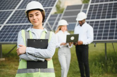 Group of investors together with young lady ecological engineer they analysing the plan of work and the efficient operation of solar batteries.