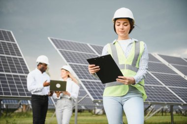 Group of investors together with young lady ecological engineer they analysing the plan of work and the efficient operation of solar batteries.