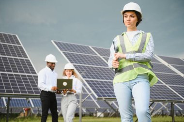 Güneş panellerinde çalışan erkek ve kadın mühendisler enerji çiftliğinde çalışıyor. Güneş enerjisi santralinde çalışan teknisyen.