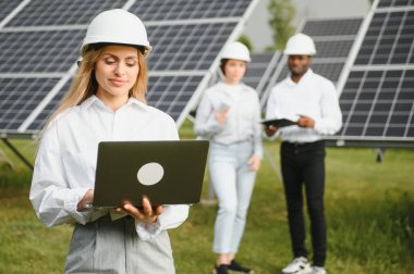 Güneş panellerinde çalışan erkek ve kadın mühendisler enerji çiftliğinde çalışıyor. Güneş enerjisi santralinde çalışan teknisyen.