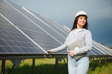Güneş enerjisi santralinin inşaat alanında miğferli kadın mühendis. Anlaşma kavramı.