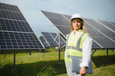 Güneş enerjisi santralinin inşaat alanında miğferli kadın mühendis. Anlaşma kavramı.