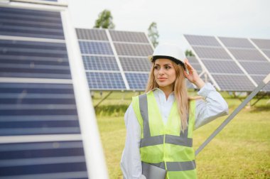 Güneş enerjisi santralinin inşaat alanında miğferli kadın mühendis. Anlaşma kavramı.