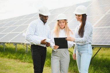 Kağıt üzerinde üç teknik mühendis planı gözden geçirip tartışıyorlar. Erkekler, kadınların nüanslarla ilgili açıklamalarını dinler..