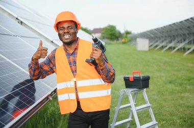 Afrikalı Amerikalı elektrikçi güneş panelleri kuruyor. Yeşil enerji.