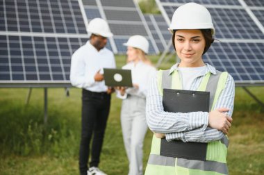 Güneş panellerinde çalışan erkek ve kadın mühendisler enerji çiftliğinde çalışıyor. Güneş enerjisi santralinde çalışan teknisyen.