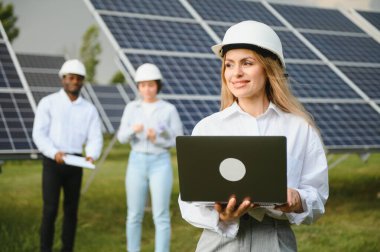 Güneş panellerinde çalışan erkek ve kadın mühendisler enerji çiftliğinde çalışıyor. Güneş enerjisi santralinde çalışan teknisyen.