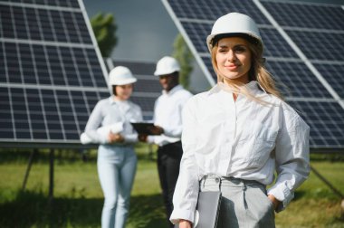 Güneş panellerinde çalışan erkek ve kadın mühendisler enerji çiftliğinde çalışıyor. Güneş enerjisi santralinde çalışan teknisyen.