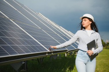 Güneş enerjisi santralinin inşaat alanında miğferli kadın mühendis. Anlaşma kavramı.