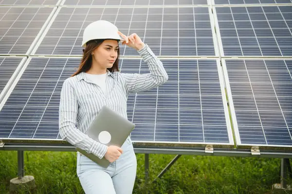 stock image Portrait of beautiful female engineer technologist standing among solar panels.