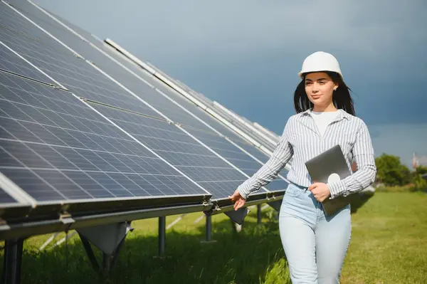 stock image Portrait of beautiful female engineer technologist standing among solar panels.